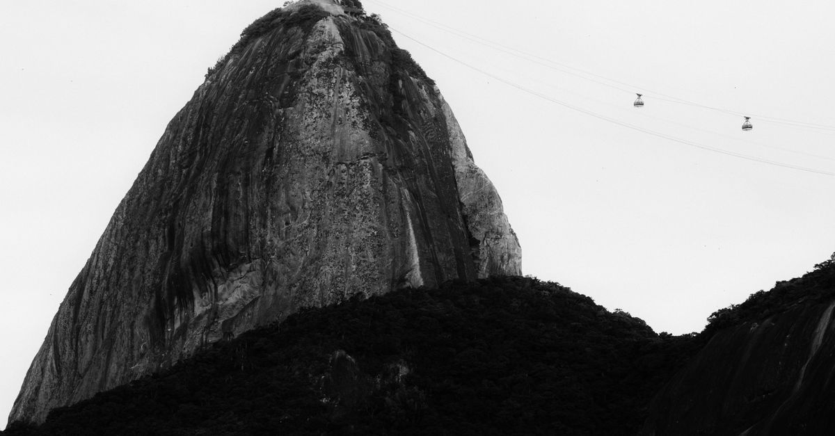 Black and white image of Sugarloaf Mountain and cable cars in Rio de Janeiro, Brazil.